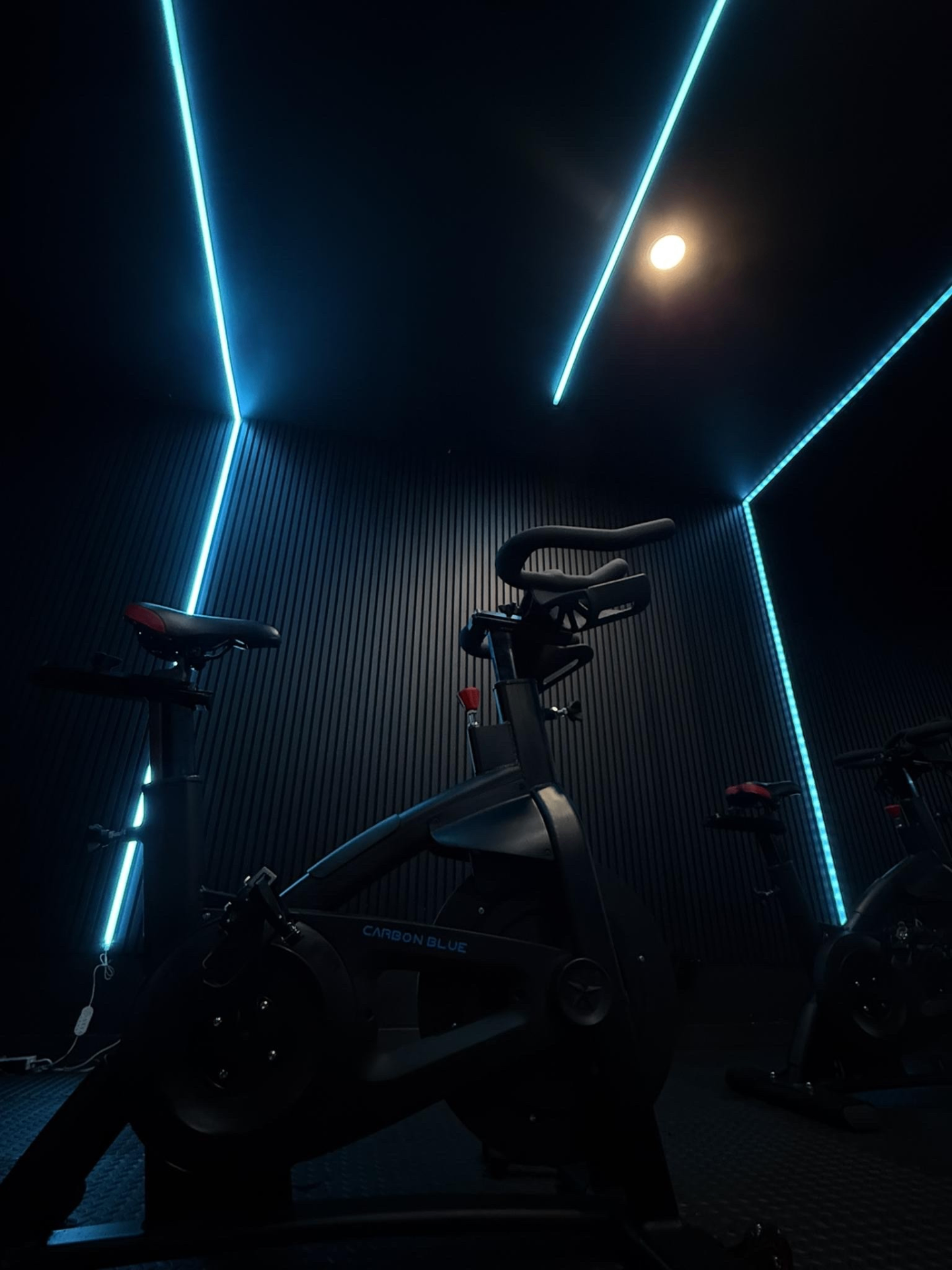Indoor cycling bike lit by blue neon strips in a dark studio
